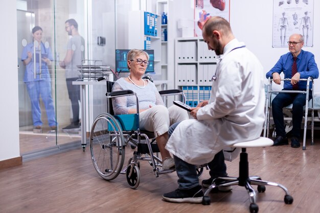 Woman with parkinson sitting in wheelchair in hospital room during medical examination