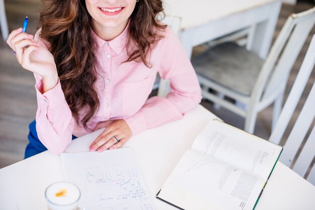 Woman with pen notebook and book at table