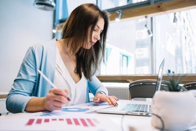 Woman with pen using laptop