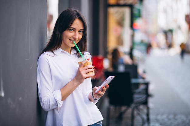 電話とコーヒーを持つ女性