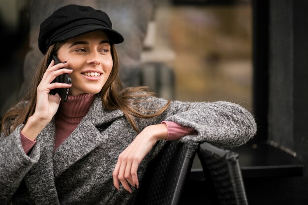 Woman with phone sitting outside cafe