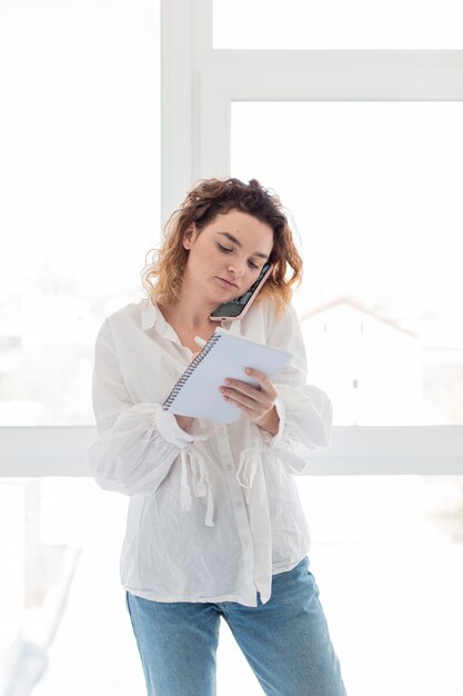 メモを取る電話を持つ女性