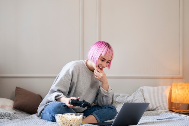 Woman with pink hair playing with a joystick on the laptop