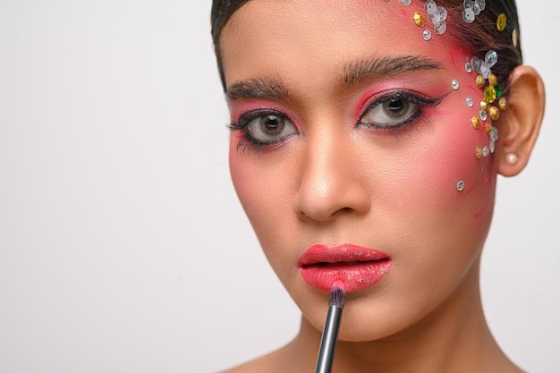 A woman with pink makeup and lipstick on her lips isolated on white