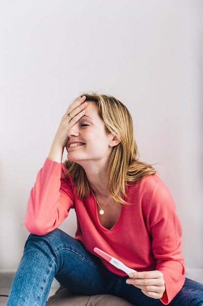 Woman with pregnancy test and hand in front of face