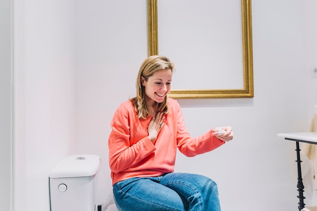 Free photo woman with pregnancy test on toilet