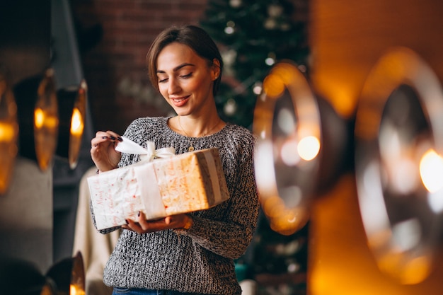 クリスマスツリーの前でプレゼントを持つ女性