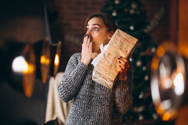 クリスマスツリーの前でプレゼントを持つ女性