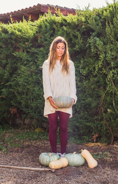 Woman with pumpkin near vegetables