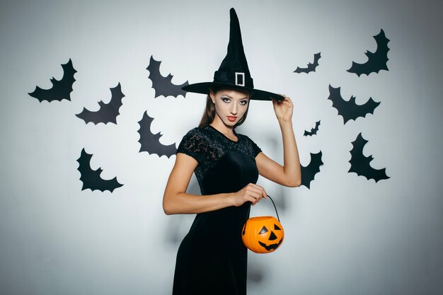 Free photo woman with pumpkin touching hat