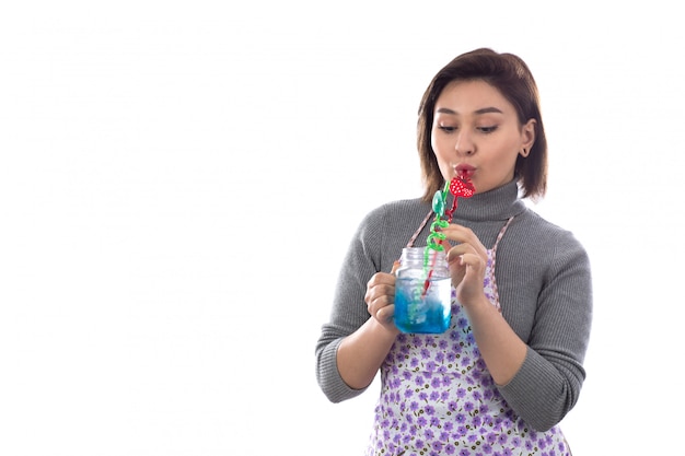 Woman with purple apron drinking blue cocktail