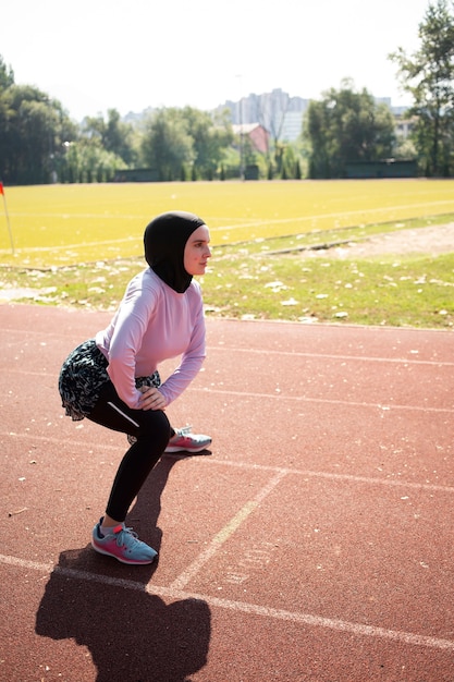 Woman with purple jacket doing side lunges