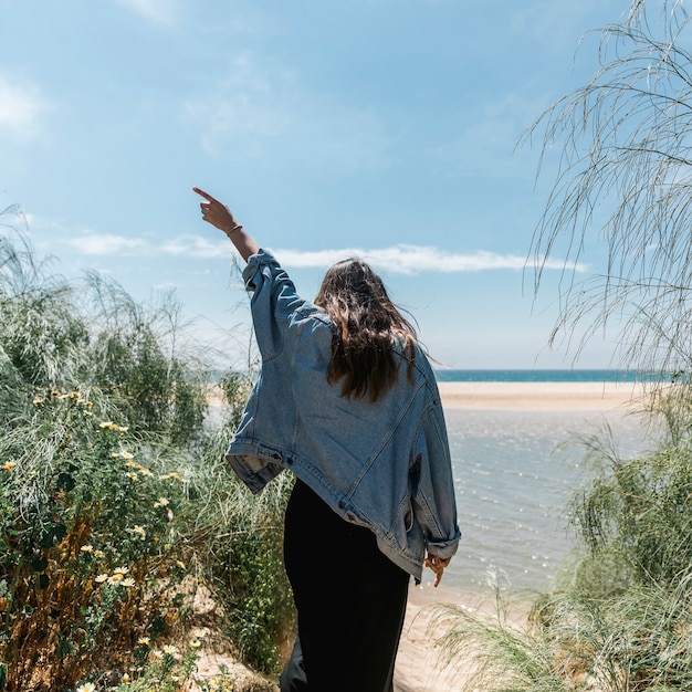 Woman with raised hand standing in tropical bushes