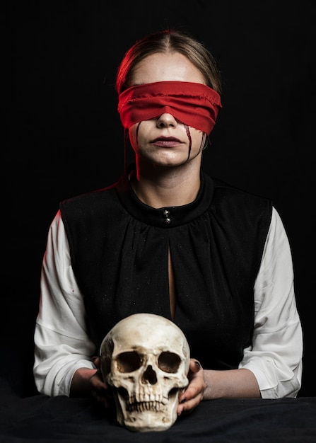 Free photo woman with red blindfold holding skull