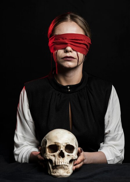Woman with red blindfold holding skull