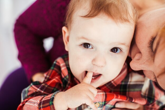 Woman with red hair holds little girl in plaid shirt 