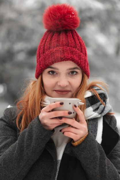 お茶のカップを保持している赤い帽子の女