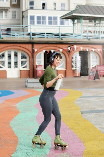 Woman with roller skates dancing and holding a bottle of water outdoors