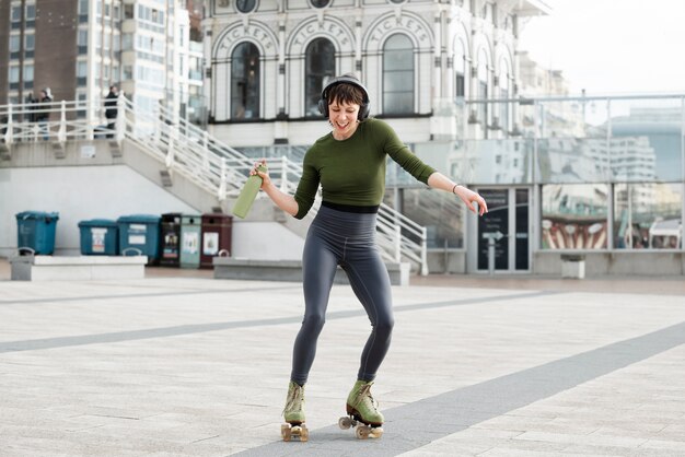 Woman with roller skates dancing and holding a bottle of water outdoors