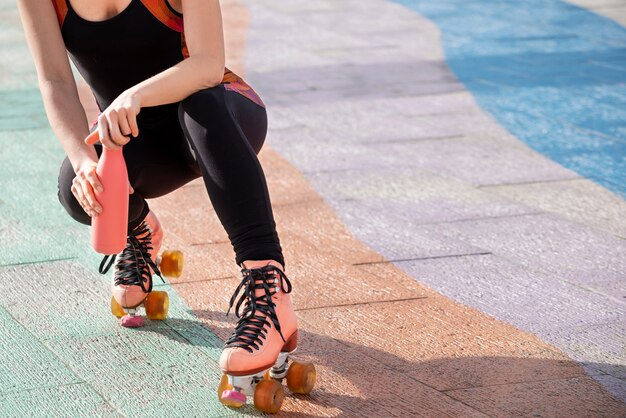 Woman with roller skates opening a bottle of water outdoors