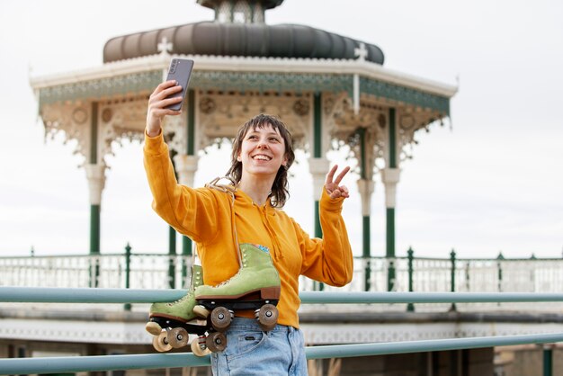 Woman with roller skates taking a selfie using her smartphone outdoors