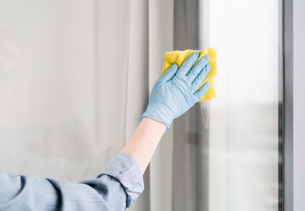 Woman with rubber glove wiping window