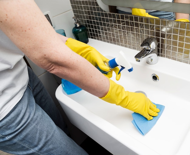 Woman with rubber gloves cleaning the sink