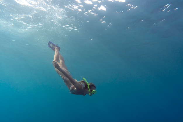 Donna con attrezzatura subacquea nuotare nell'oceano