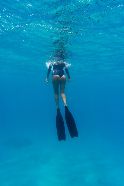 Donna con attrezzatura subacquea nuotare nell'oceano