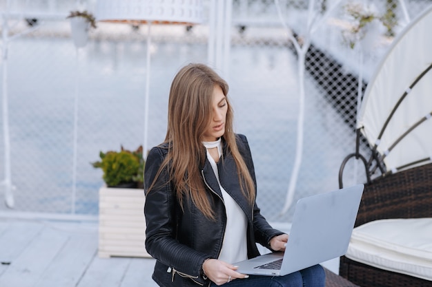 Foto gratuita donna con sfondo di porto con un computer portatile sulle gambe