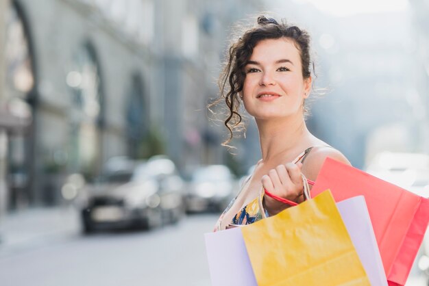 幸せに買い物をするいくつかの紙袋を持つ女性