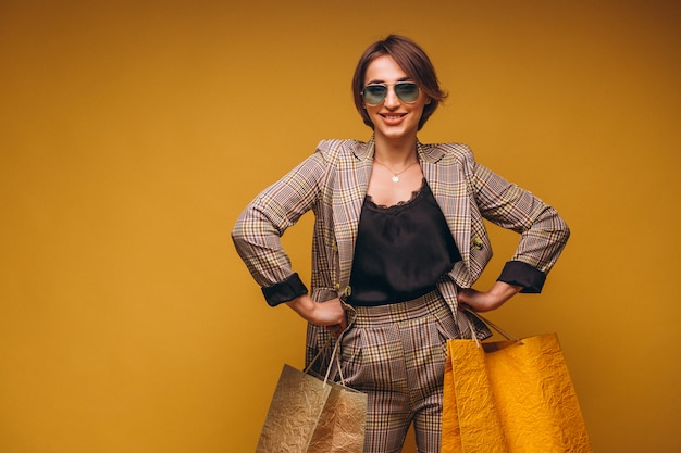 Foto gratuita donna con i sacchetti della spesa in studio su fondo giallo isolato