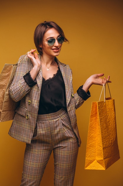 Woman with shopping bags in studio on yellow background isolated