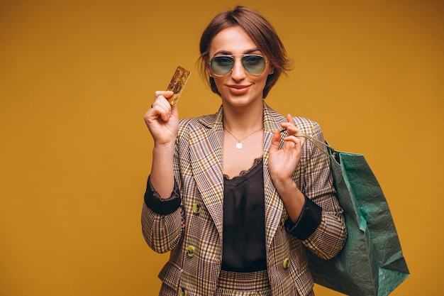 Woman with shopping bags in studio on yellow background isolated