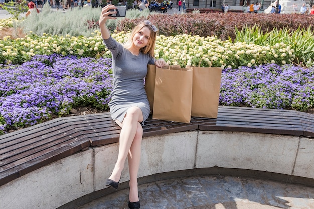 Donna con i sacchetti della spesa che prendono selfie nel parco