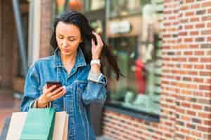 Free photo woman with shopping bags using smartphone in mall