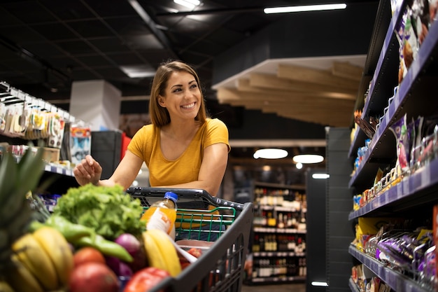 woman with shopping cart buying food at supermarket