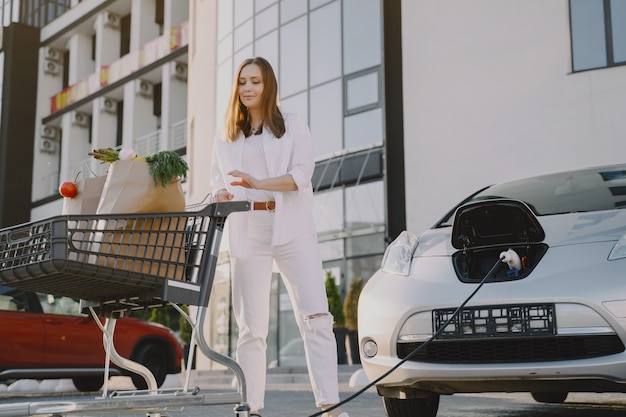 彼女の車でショッピングカートを持つ女性