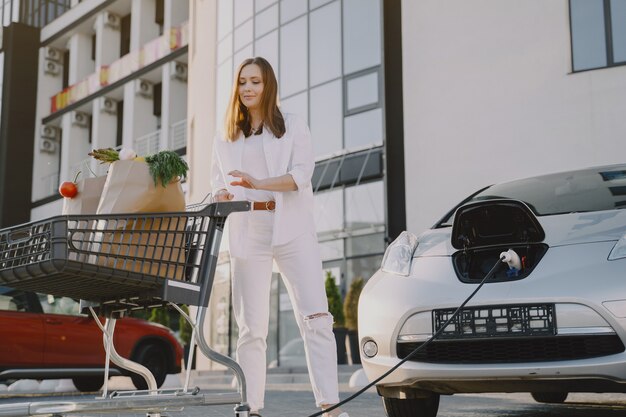 Woman with a shopping cart by her car