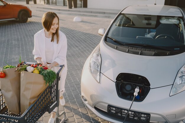 彼女の車でショッピングカートを持つ女性