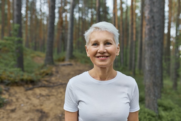 woman with short hairstyle posing outdoors with pine trees