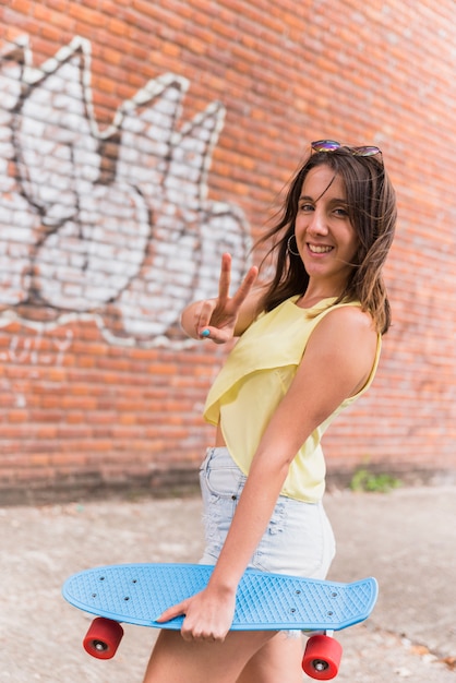 Free photo woman with skateboard showing peace gesture