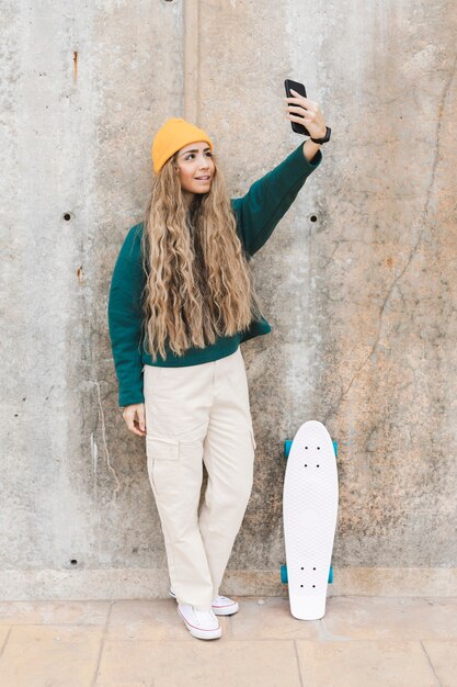 Woman with skateboard taking selfies