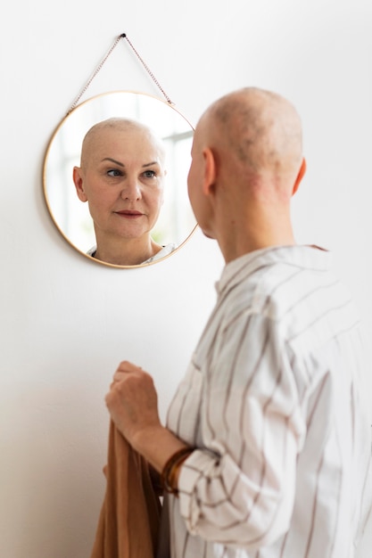 Free photo woman with skin cancer looking in the mirror