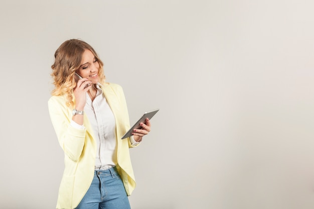 Woman with smartphone on ear and tablet