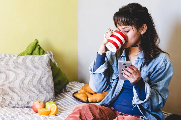 女性、スマートフォン、ホットドリンク