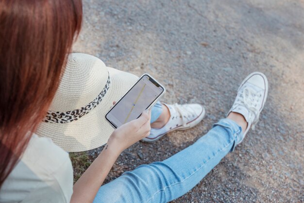 彼女の車にもたれてスマートフォンを持つ女性