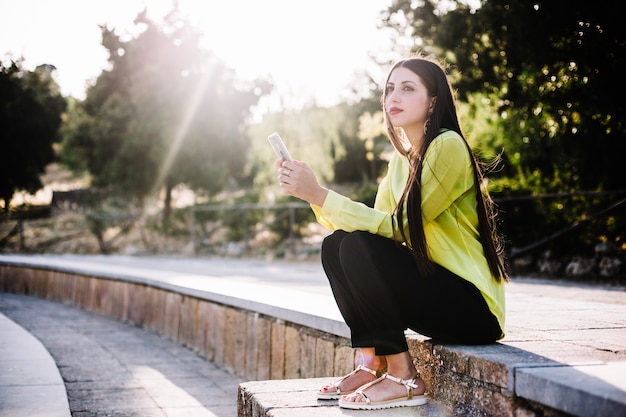 Foto gratuita donna con smartphone che guarda lontano