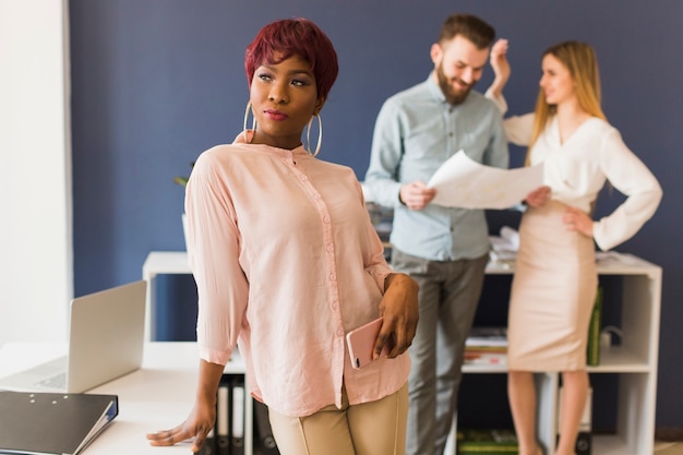 Woman with smartphone near working colleagues