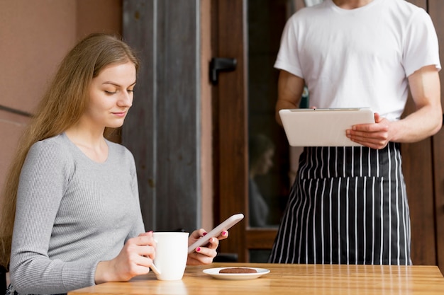 Woman with smartphone ordering coffee